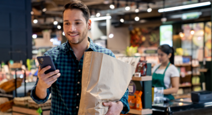 man looking at phone holding paper bag